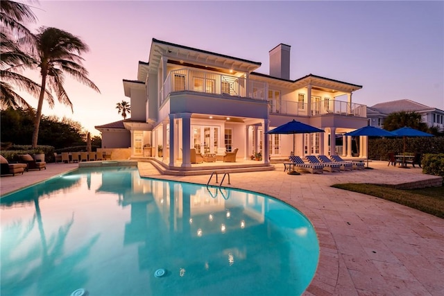 pool at dusk with a patio area