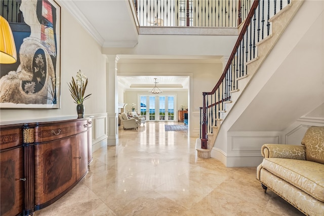 foyer entrance with crown molding, decorative columns, and french doors