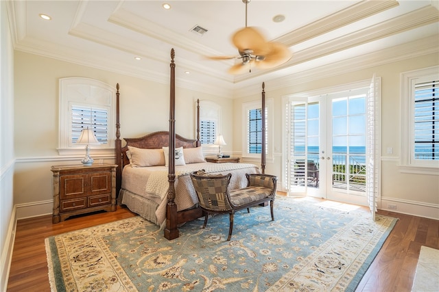 bedroom featuring access to exterior, a tray ceiling, french doors, and a water view