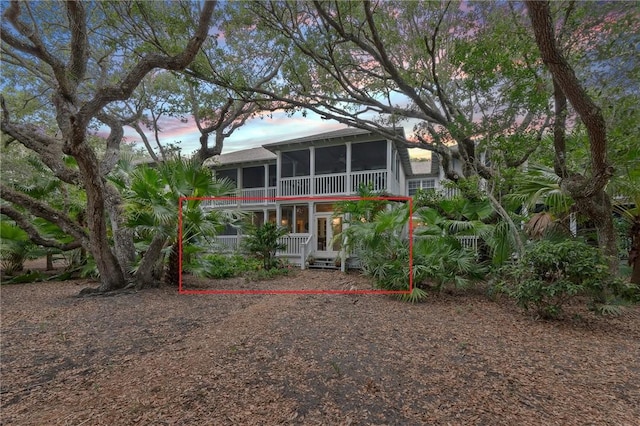 back house at dusk featuring a sunroom