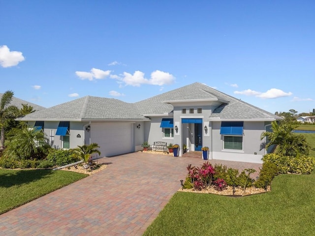 view of front of property featuring stucco siding, an attached garage, decorative driveway, and a front lawn