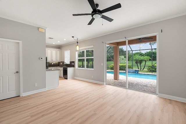 unfurnished living room with ceiling fan, sink, ornamental molding, and light wood-type flooring