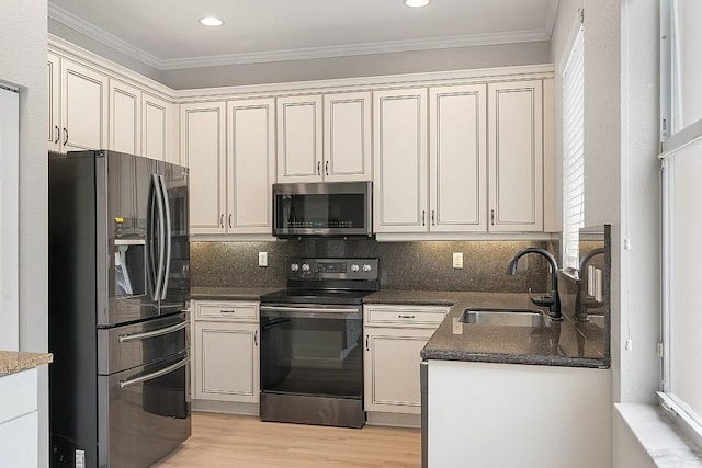 kitchen featuring appliances with stainless steel finishes, crown molding, cream cabinetry, and sink