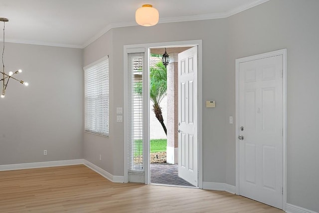 entrance foyer with light wood-type flooring, an inviting chandelier, and ornamental molding