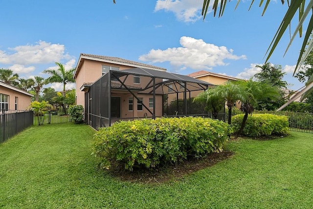 rear view of property with glass enclosure and a lawn