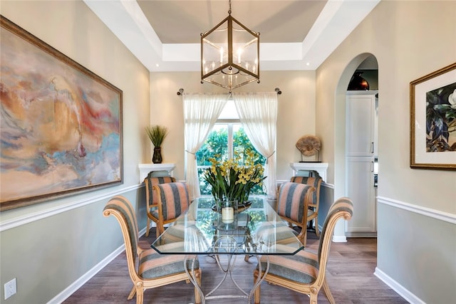 dining room with a notable chandelier, dark hardwood / wood-style flooring, and a tray ceiling