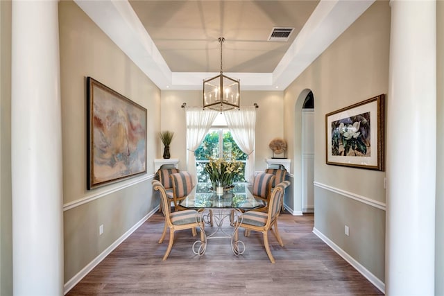 dining area featuring hardwood / wood-style flooring, a chandelier, and a raised ceiling