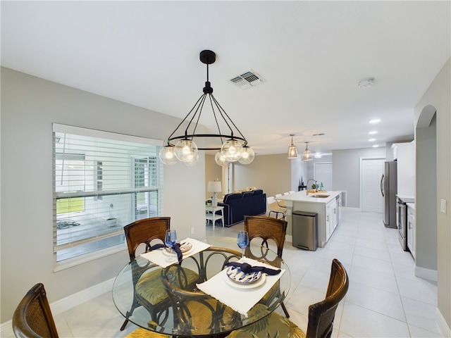 tiled dining space with a notable chandelier and sink