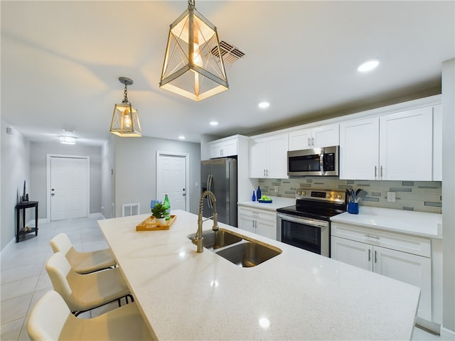 kitchen featuring white cabinetry, sink, appliances with stainless steel finishes, a kitchen breakfast bar, and pendant lighting