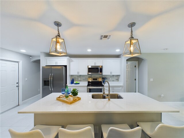 kitchen with white cabinetry, appliances with stainless steel finishes, pendant lighting, decorative backsplash, and sink