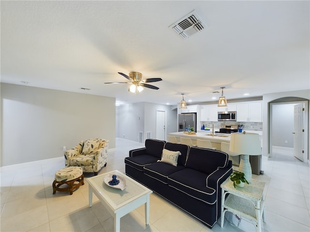 living room with ceiling fan, sink, and light tile patterned floors