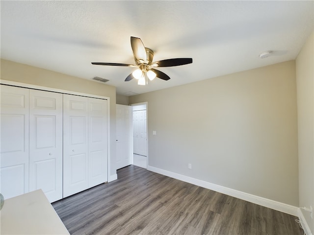 unfurnished bedroom with dark hardwood / wood-style flooring, a closet, a textured ceiling, and ceiling fan