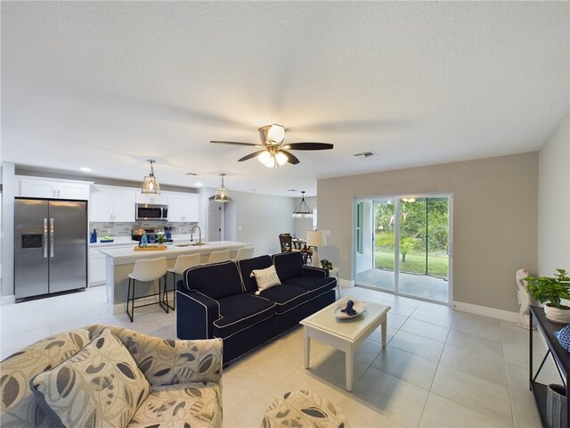 tiled living room featuring sink, a textured ceiling, and ceiling fan