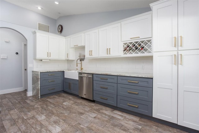 kitchen with sink, vaulted ceiling, stainless steel dishwasher, decorative backsplash, and white cabinets