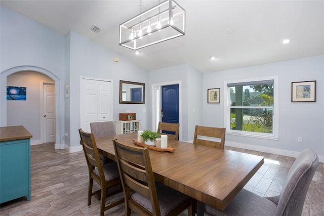 dining room with lofted ceiling, light hardwood / wood-style floors, and an inviting chandelier