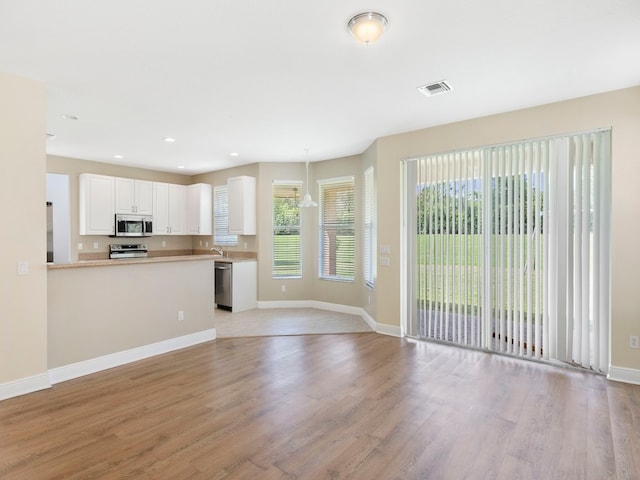 kitchen featuring white cabinetry, kitchen peninsula, stainless steel appliances, and light hardwood / wood-style flooring