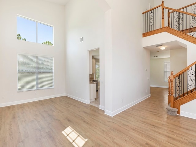 interior space with a towering ceiling and light hardwood / wood-style floors