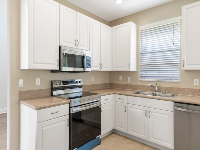 kitchen featuring white cabinets, sink, light tile patterned flooring, and stainless steel appliances