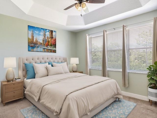 bedroom featuring light colored carpet, ceiling fan, and a tray ceiling