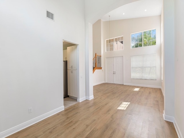 entryway with light hardwood / wood-style floors, plenty of natural light, and high vaulted ceiling