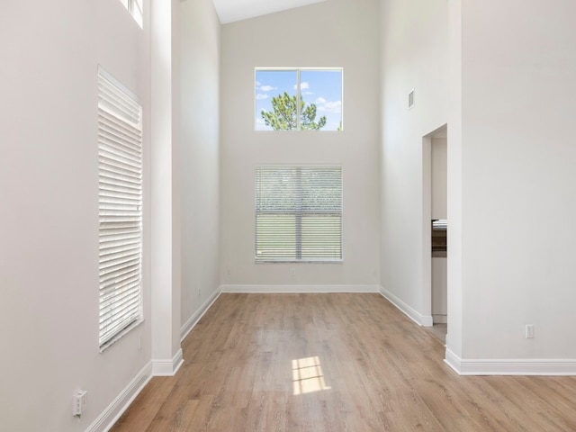 unfurnished room featuring high vaulted ceiling and light hardwood / wood-style floors