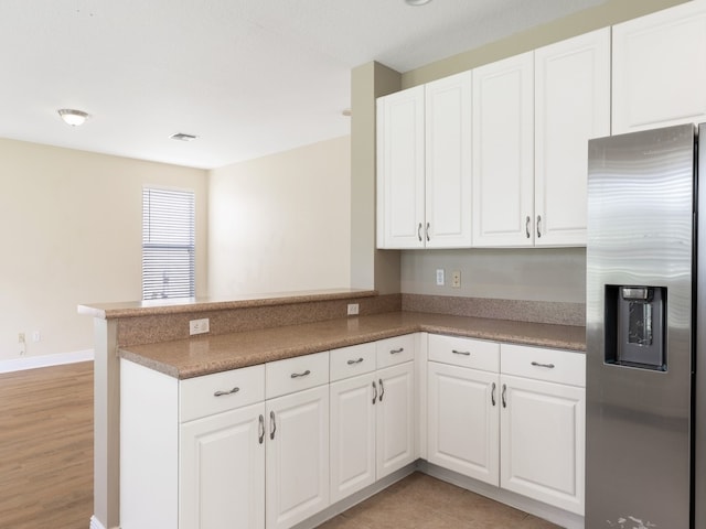 kitchen with white cabinetry, kitchen peninsula, light hardwood / wood-style floors, and stainless steel fridge