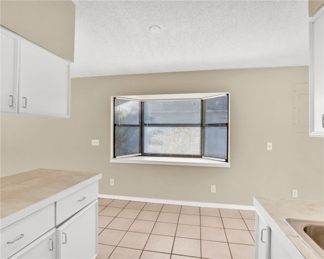 kitchen featuring a textured ceiling, white cabinetry, and light tile patterned flooring