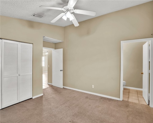 unfurnished bedroom featuring ceiling fan, ensuite bathroom, light carpet, and a closet