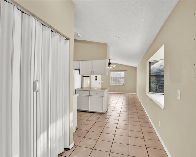 kitchen featuring ceiling fan, white cabinetry, light tile patterned flooring, and lofted ceiling