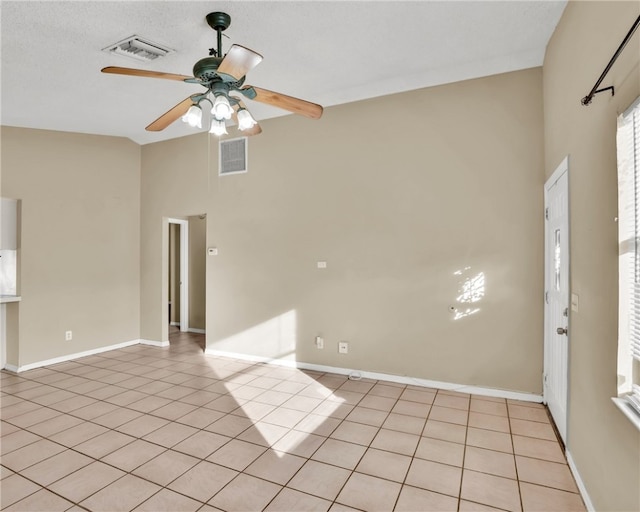 tiled empty room with a textured ceiling, high vaulted ceiling, and ceiling fan