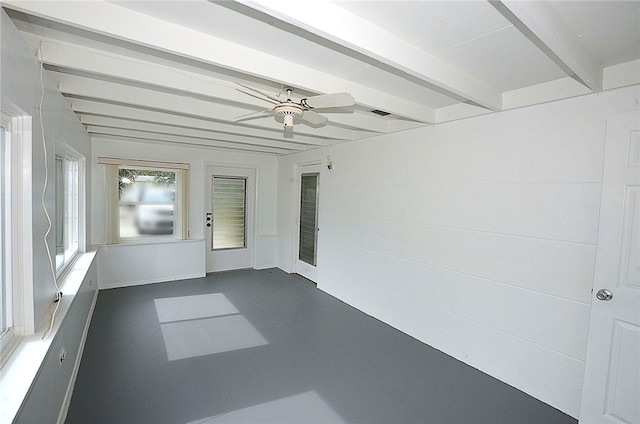 unfurnished sunroom featuring beamed ceiling and ceiling fan