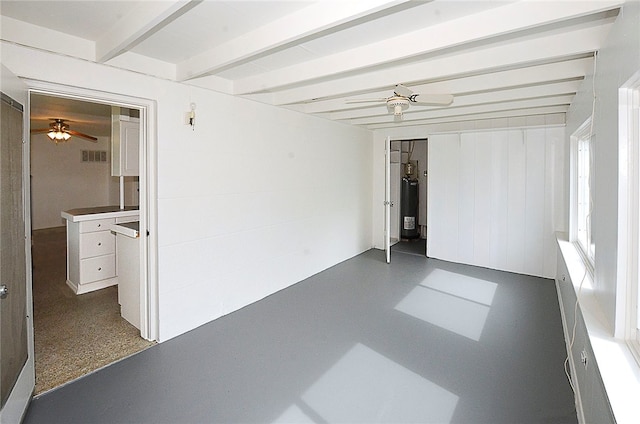 unfurnished room featuring beamed ceiling and water heater