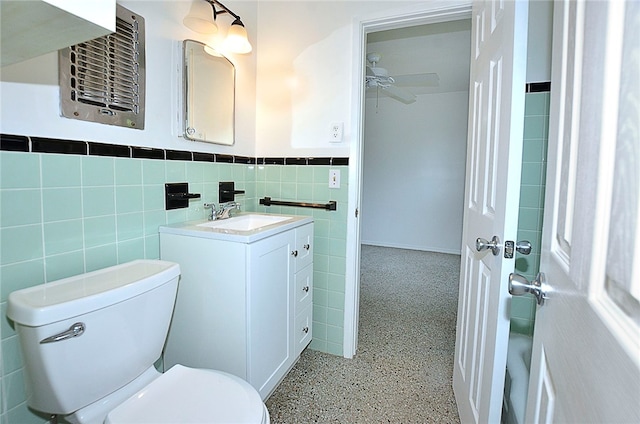 bathroom with toilet, vanity, tile walls, and ceiling fan