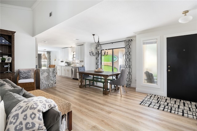 living room with an inviting chandelier, crown molding, and light hardwood / wood-style flooring