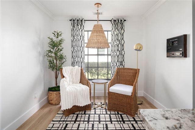 living area with crown molding and light hardwood / wood-style flooring