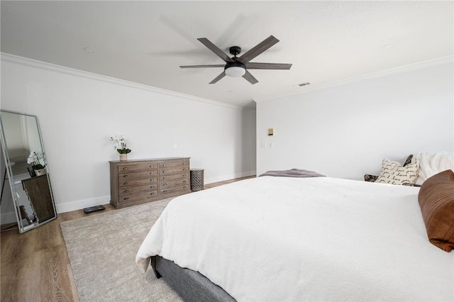 bedroom with crown molding, light hardwood / wood-style floors, and ceiling fan