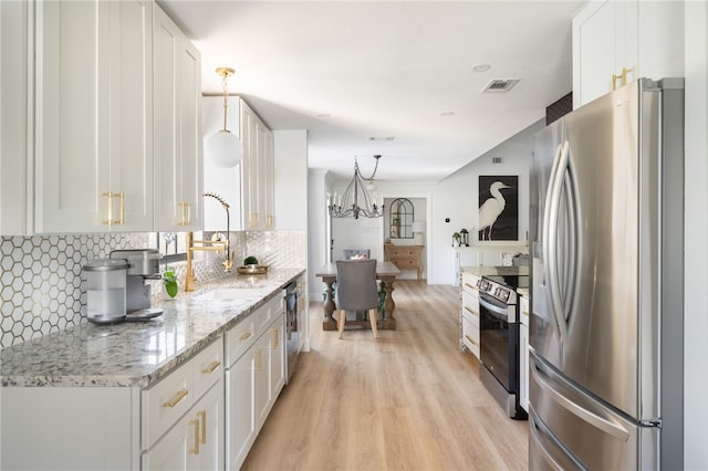 kitchen with light stone counters, appliances with stainless steel finishes, tasteful backsplash, and white cabinets