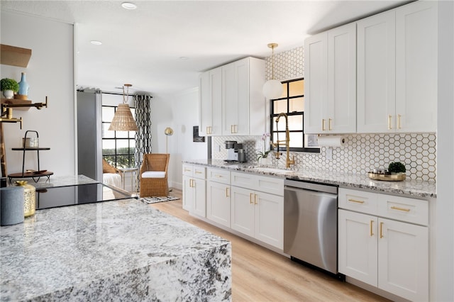 kitchen featuring pendant lighting, white cabinetry, stainless steel dishwasher, light stone counters, and light hardwood / wood-style flooring