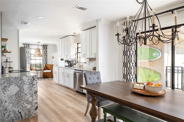 kitchen with light stone countertops, stainless steel dishwasher, sink, and white cabinets