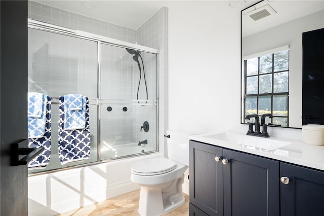 full bathroom featuring enclosed tub / shower combo, vanity, and toilet