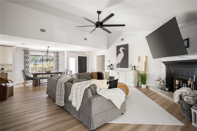 living room with high vaulted ceiling, a fireplace, ornamental molding, ceiling fan, and light hardwood / wood-style floors