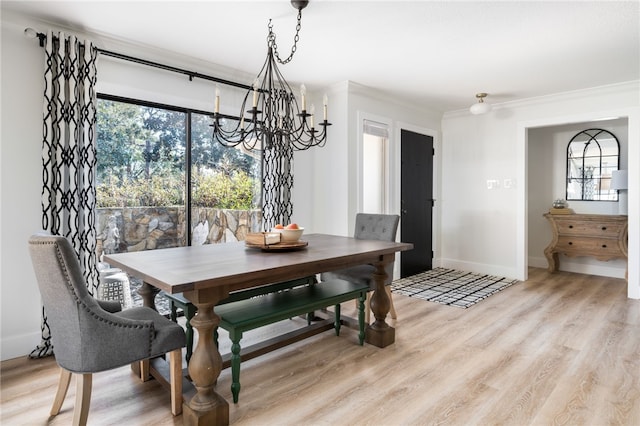 dining space with an inviting chandelier, ornamental molding, and light hardwood / wood-style floors