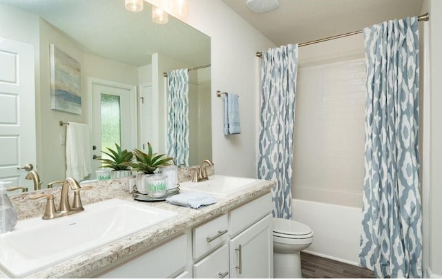 full bathroom with double vanity, shower / bath combo with shower curtain, a sink, and toilet