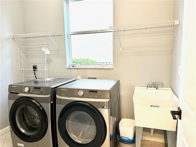 laundry area featuring a sink, laundry area, washing machine and dryer, and baseboards