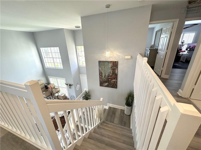 stairs featuring wood finished floors, a towering ceiling, and baseboards