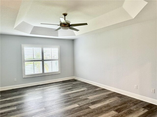 1886 Grey Falcon Cir SW, Vero Beach, FL 32962 - empty room with dark wood-style flooring, a tray ceiling, baseboards, and a ceiling fan