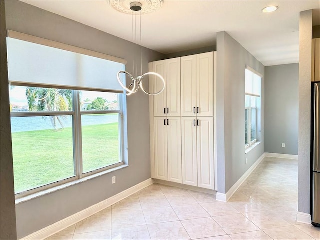 unfurnished dining area with baseboards and light tile patterned flooring