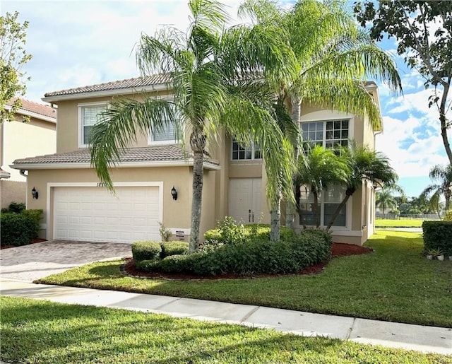 view of front facade featuring a garage, a front lawn, decorative driveway, and stucco siding