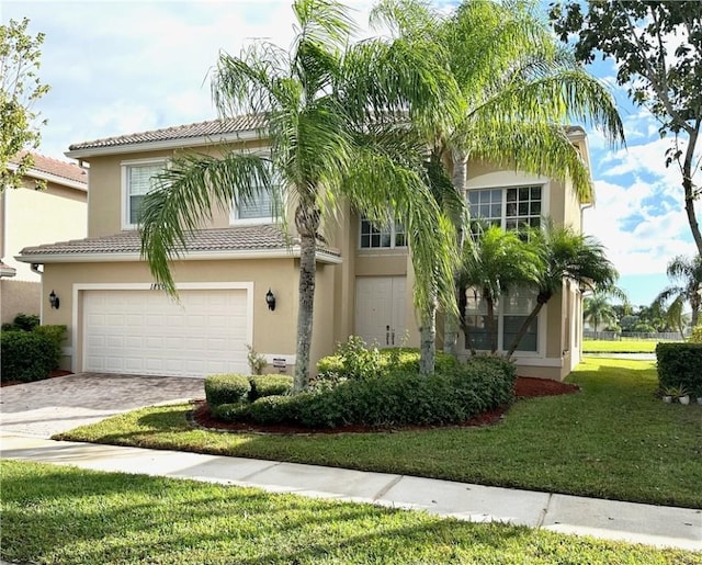1886 Grey Falcon Cir SW, Vero Beach, FL 32962 - view of front of house with a garage, stucco siding, driveway, a front lawn, and a tiled roof