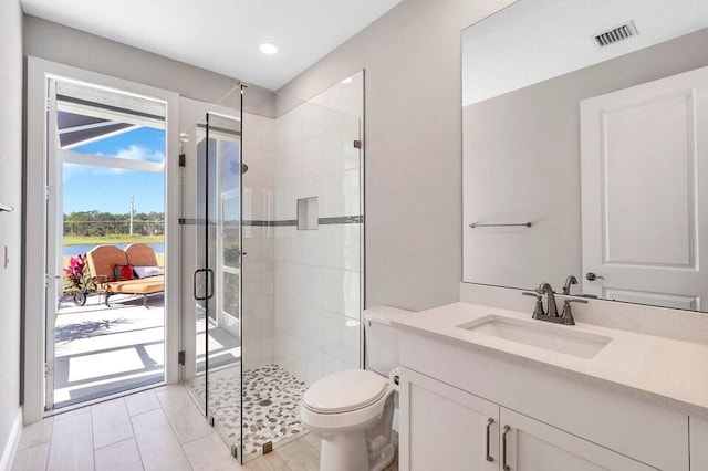 bathroom with vanity, toilet, and a shower with door